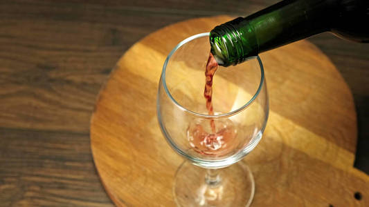 熟练的侍酒师把红酒从瓶子里倒进玻璃杯里。闭合。