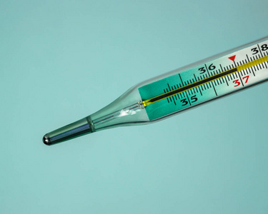 医用水银温度计显示体温37摄氏度.蓝色背景的特写镜头.照片