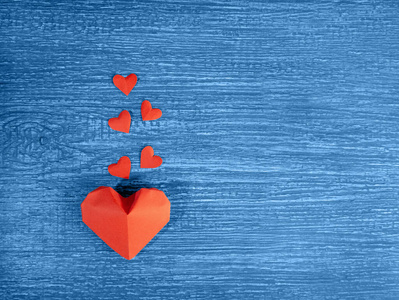 纸红色的心在一个古老的，蓝色，有纹理的木质背景上。爱的象征。情人节。生日。