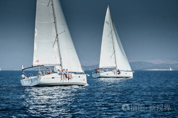 帆船比赛帆船赛水上的倒影激烈的竞争船尾的船很多颜色鲜艳背景是岛