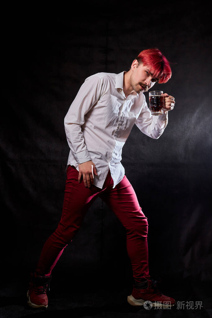 有趣的男人,脸上带着情绪,手里拿着啤酒杯,背景是黑色的.酒鬼