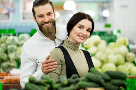 一对健康夫妇在超市购物时看着水果和蔬菜的肖像。