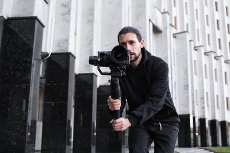 年轻的专业摄像师在3轴万向节稳定器上手持专业摄像机.