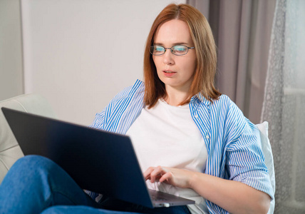 女自由职业者躺在沙发上用电脑工作