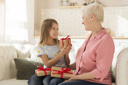 可爱的孩子和奶奶在家里交换节日礼物照片