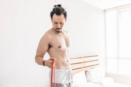 男人在家里用阻力带伸展肌肉。
