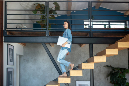 年轻女子下楼,腋下夹着笔记本,面带微笑日本寿司卷用