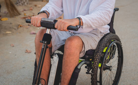 坐在轮椅上的残疾人在沙滩上骑着电动滑板车