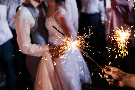 新娘新郎和手持彩灯的宾客手上拿着闪亮的珠宝照片