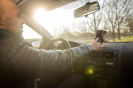 男子在开车前在手机上设置GPS，在开车时保持稳定，运输理念