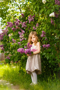 blonde girl in a pink dress near a lilac flowers 