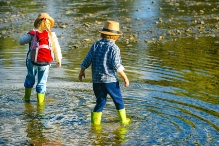 可爱的金发女孩和男孩在小溪里玩耍.