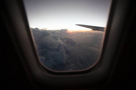 从云层上的飞机窗口看日出。