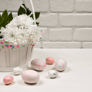 复活节概念。复活节粉红彩蛋在白色墙壁背景的木桌上的一个花篮旁边。题词的地方。明信片。
