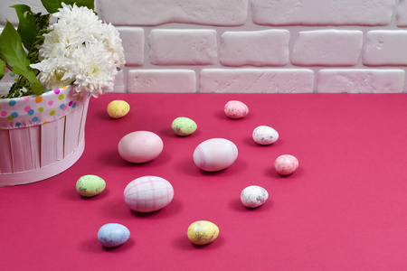 复活节概念。复活节彩蛋在白色墙壁背景的红色桌子上的一个花篮旁边。题词的地方。贺卡。