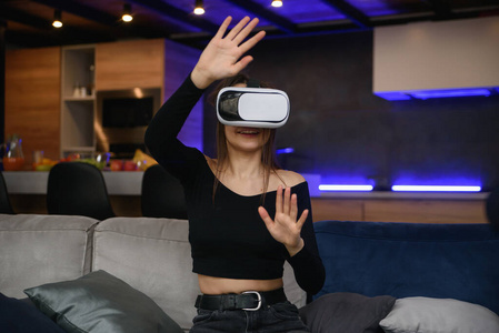 虚拟现实。兴奋的千禧一代女孩用虚拟现实耳机在室内玩游戏。选择性聚焦