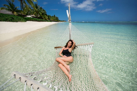 岛上热带海滩上吊床上的女人。