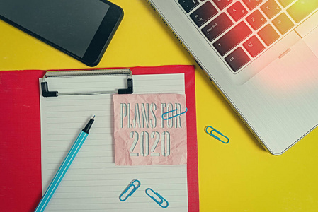 手写文本计划在2020年。概念意味着一个意图或决定，一个人要做什么笔记本电脑剪贴板表剪辑标记笔记智能手机彩色背景。
