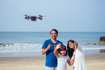 快乐的印度家庭正在果阿海滩遥控操作无人机