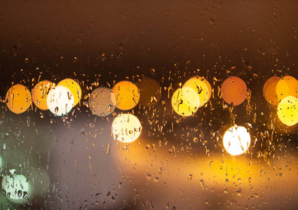 夜市灯光和雨滴在玻璃上的散焦，背景，复制空间。模糊