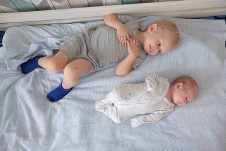 Little brother hugging her newborn baby. Toddler kid meeting new