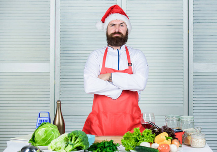 做美味又快捷的节日大餐。最后一分钟圣诞晚餐的主意。食谱简单，烹饪时间少。圣诞老人帽胡子时髦的男子穿着烹饪围裙。家常菜