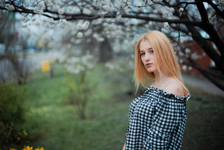 美丽的年轻金发女孩在花丛中