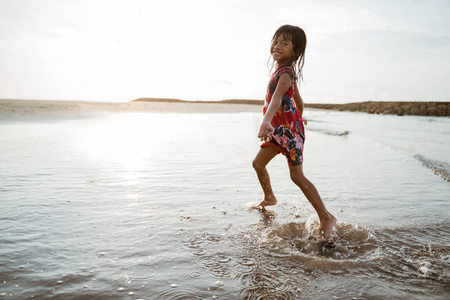 小女孩一边玩水一边在沙滩上跑图片