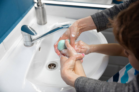 母亲在浴室里仔细地给儿子洗手.预防感染和肺炎病毒传播照片