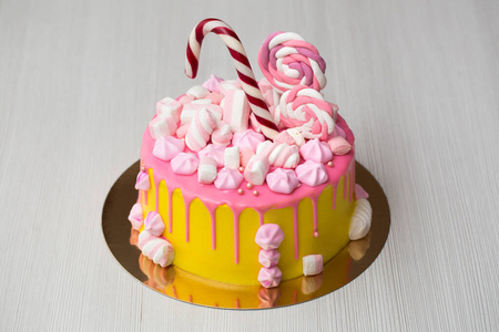 儿童黄色蛋糕加粉红色糖霜，蛋白酥皮和糖果。