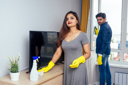 印度年轻夫妇搬进新家，打扫和打开大窗户，时尚的黄色窗帘背景
