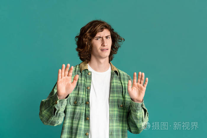 不满的年轻人在绿松石背景上做否认手势