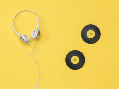 黄色背景的白色耳机和黄色乙烯基光盘。