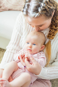 一位年轻漂亮的母亲怀里抱着一个蓝眼睛的2个月大的小女儿。新生儿。