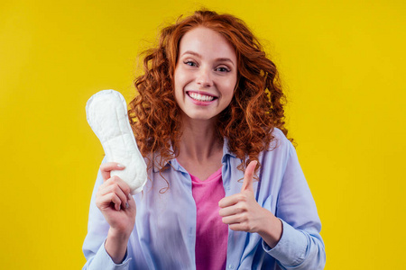 年轻的红头发卷曲的姜汁女商人穿着蓝色衬衫拿着卫生巾选择卫生棉工作