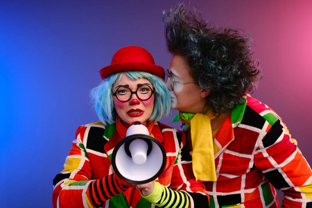 Two clowns a man and a woman with bright makeup in colored costu