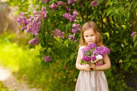 beautiful little girl near a lilac flowers 