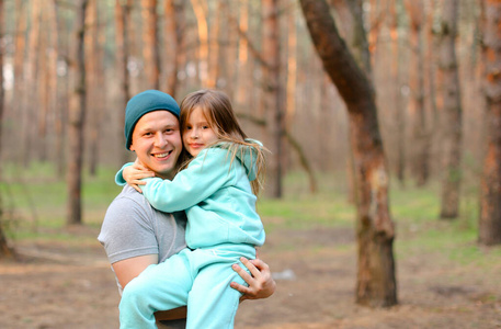 年轻快乐的父亲抱着女儿在公园里。