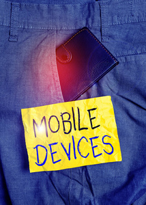 文字书写文字移动设备。便携式计算设备的商业概念，如智能手机或平板电脑男子裤子前口袋里的小钱包，靠近记号纸。