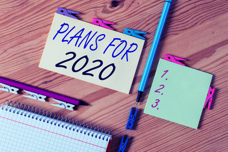 展示2020年计划的概念性手稿。商业照片展示了一个意图或决定，一个人将要做什么彩色皱折纸木地板背景衣夹。