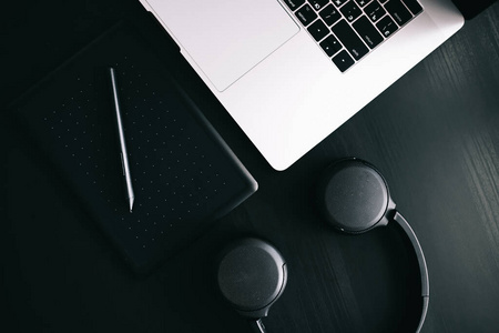 Dark modern workplace with a graphic tablet, laptop, wireless he