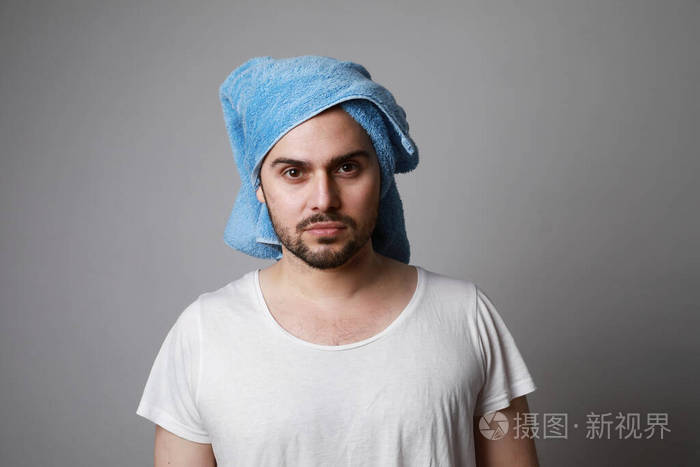 胡子男人用毛巾裹在头上穿着白色t恤灰色隔离护发理念