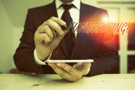 显示募捐的文字标志。概念照片寻求为慈善事业筹集资金支持或促使男性穿正装呈现使用高科技智能手机。