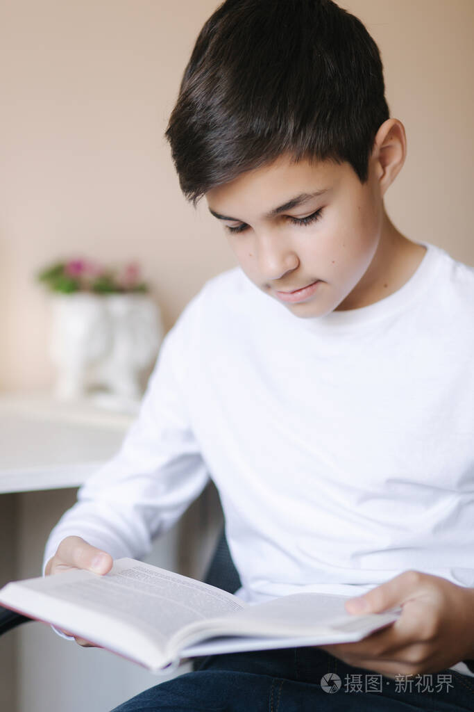 小男孩坐在书桌旁看书检疫期间在家学习