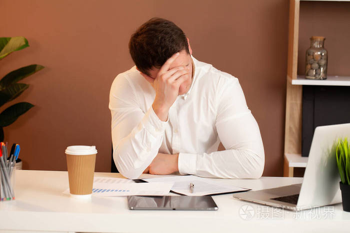 在公司办公室办公桌旁工作的疲惫员工