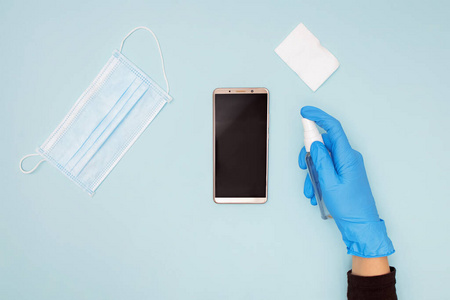 手戴防护手套清洁消毒手机预防covid-19冠状病毒病.照片