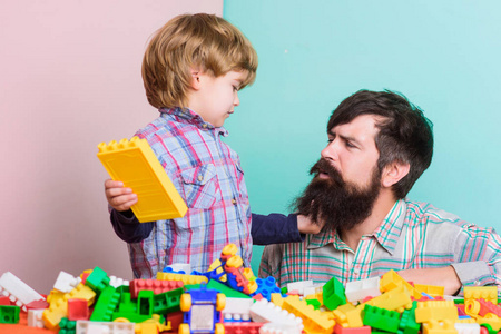 我来帮你。用五颜六色的构装玩具建造家园。儿童发展。父子俩玩玩具游戏。小男孩和爸爸一起玩。家庭休闲快乐。教育砖块玩具