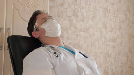 疲惫的医生戴着防护面罩和护目镜在诊所休息.