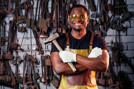 锤子行业小企业非洲概念身着历史服装的美国男子正在铁砧上锤击。铁匠铸造金属制品
