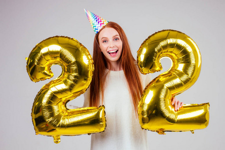 姜黄色女人与生日帽号角手持气球22周年纪念数字工作室白色背景照片